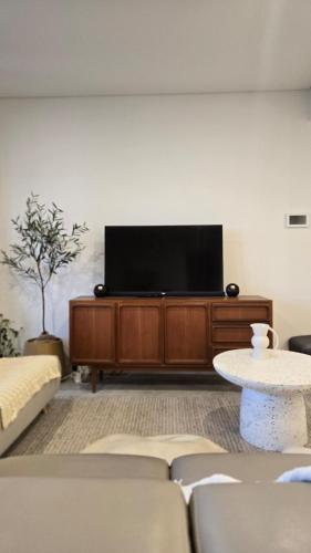 a living room with a flat screen tv on a entertainment center at Rivi Retreat - Brand New Luxury & Central in Sydney
