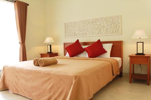 a bedroom with a large bed with red pillows at Mona Homestay in Sanur