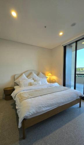a bedroom with a large bed with white sheets and pillows at Rivi Retreat - Brand New Luxury & Central in Sydney