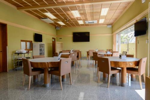 uma sala de jantar com mesas e cadeiras e uma TV em ビジネスホテル旅館本陣 em Kisarazu