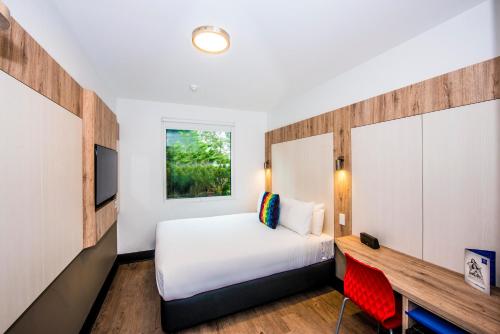 a bedroom with a bed and a desk and a television at ibis budget Sydney Airport in Sydney