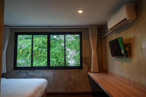 a bedroom with a bed and a window with trees at Wat We See Bangkok Hostel in Bangkok