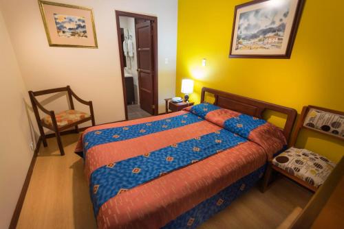 a bedroom with a bed and a chair in it at Hotel Francés La Maison in Pasto