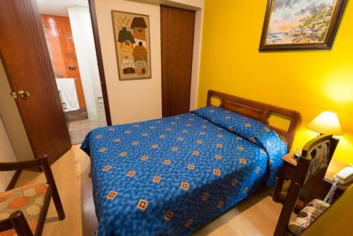 a bedroom with a bed with a blue comforter at Hotel Francés La Maison in Pasto