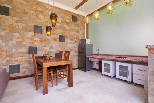 a kitchen with a table and chairs and a stone wall at Octopus Villas in Tejakula