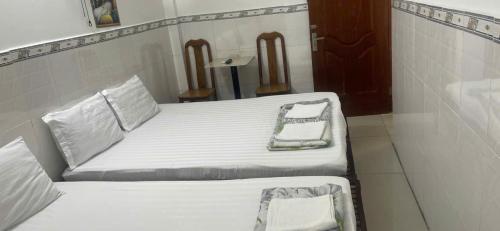 deux lits dans une chambre avec draps et oreillers blancs dans l'établissement Cường Phú Hotel Hồ Chí Minh, à Hô-Chi-Minh-Ville