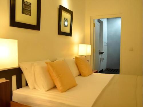 ein Schlafzimmer mit einem weißen Bett und gelben Kissen in der Unterkunft 26 Loversleap Cottage in Nuwara Eliya