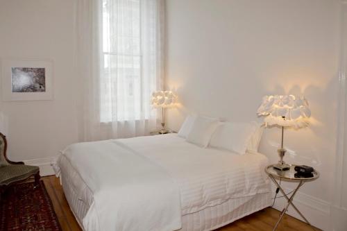 a white bedroom with a white bed and two lamps at Mollisons in Kyneton