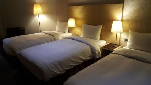 a hotel room with two beds and two lamps at 麗馨商旅七賢館 in Kaohsiung