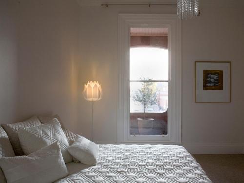 a white bedroom with a bed and a window at Mollisons in Kyneton