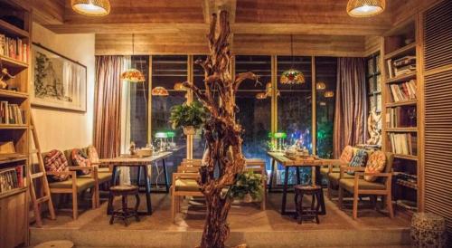 a room with tables and chairs and a tree in it at Meizhou See You Again Hostel in Meizhou