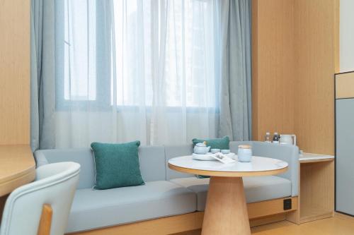 una sala de estar con un sofá y una mesa en JI Hotel Shanghai Daning Yichuan Road, en Shanghái
