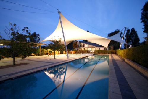 a swimming pool with a white shade over it at Chateau Elan At The Vintage in Pokolbin