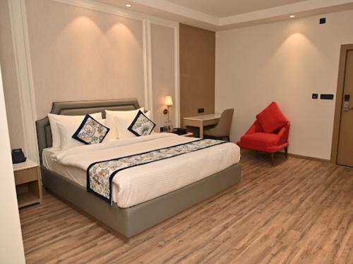 a hotel room with a bed and a red chair at Arth Boutique and Hotel in Kota