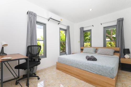 Sisters Ari 2-bedrooms house, Bang Tao beach في Ban Thalat Choeng Thale: غرفة نوم بها سرير ومكتب ونوافذ