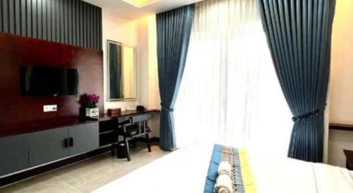 a bedroom with a bed and a tv and a window at Sky Boutique Kampot in Phumĭ Bœ̆ng Phlŏng (2)