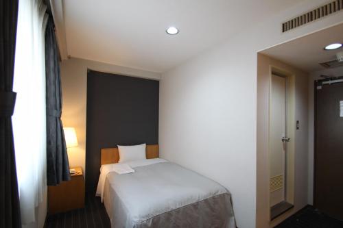 a small bedroom with a bed and a window at Hotel Il Viale Hachinohe Annex in Hachinohe