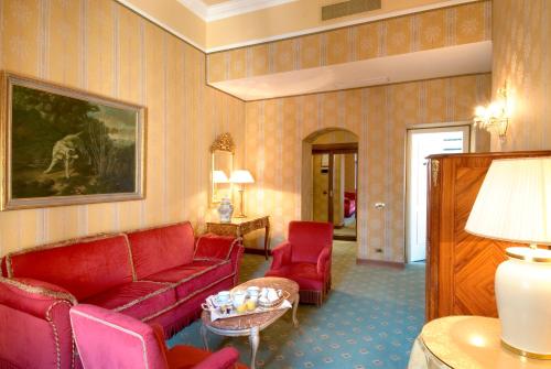 a living room with a red couch and red chairs at Sina Brufani in Perugia