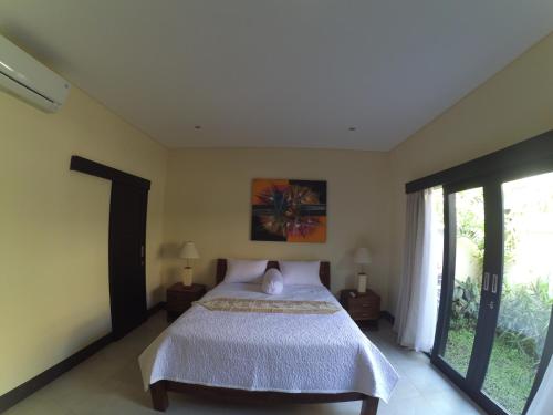 una camera con un letto e una grande finestra di Dana Jaya Villa ad Ubud