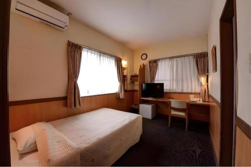 嘉間良にあるDeigo Hotelのベッドとパソコン付きの机がある寝室