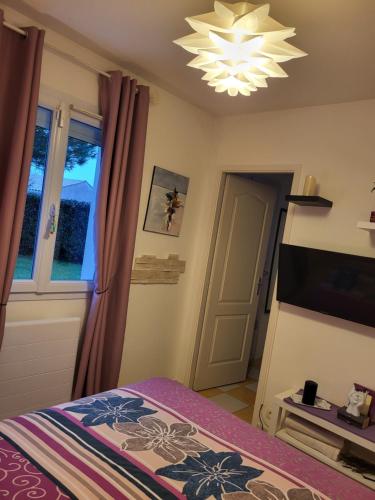 Schlafzimmer mit einem Bett, einem TV und einem Kronleuchter in der Unterkunft Brigitte in Saujon