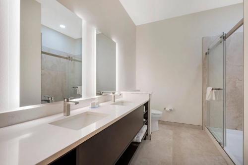 een witte badkamer met twee wastafels en een douche bij The J Hotel Dunedin Clearwater, an Ascend Collection Hotel in Dunedin