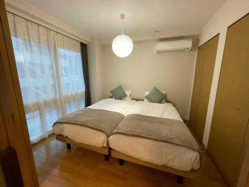 a bedroom with a large bed with a window at カピテーヌ琴似 in Sapporo