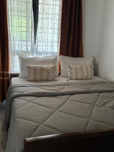 ein großes Bett mit zwei Kissen vor dem Fenster in der Unterkunft The Coffee Retreat in Mudigere