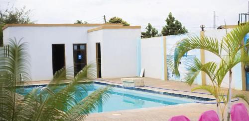 a swimming pool in front of a white house at Madonna 1BR Apartment with Fast WiFi and Pool in Morogoro