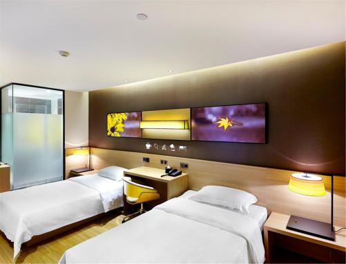 Habitación de hotel con 2 camas y TV en la pared en 7Days Premium Guilin Seven star International Exhibition Center en Guilin