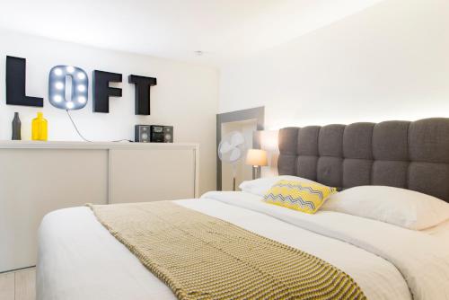 a bedroom with a large bed with a gray headboard at Unsejouranantes- Loft Cassard in Nantes