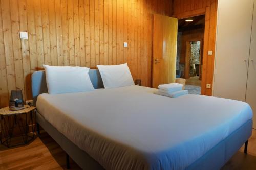 a large white bed in a room with wooden walls at Casas de Fralães in Grimancelos