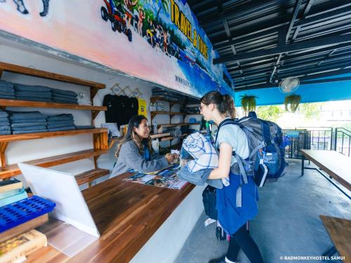 twee mensen staan aan een toonbank in een winkel bij Bad Monkey Samui Hostel in Chaweng Beach