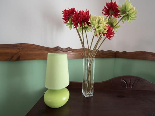 a vase with red flowers and a candle on a table at Luxury Central apartment in Sibiu in Sibiu