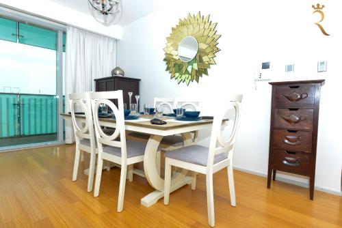 ein Esszimmer mit einem Tisch mit Stühlen und einem Spiegel in der Unterkunft Golden Timber 2BR Al Raha Family Retreat in Abu Dhabi
