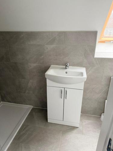 La salle de bains est pourvue d'un lavabo blanc et d'une baignoire. dans l'établissement Modern 3 Bed with 3 Baths and Parking, Near Centre, à Bredbury