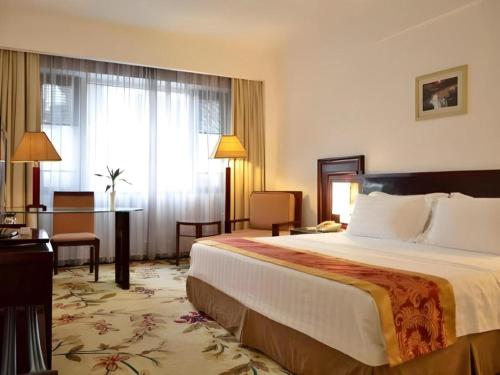 a hotel room with a large bed and a desk at Hong Ye Hotel in Guangzhou