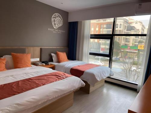 LaoyachenにあるShell Zhengzhou North Third Ring University Science and Technology Park Hotelのベッドが2つと窓があるホテルの部屋