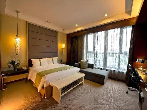 a bedroom with a large bed and a large window at GreenTree Inn Rizhao Train Station in Rizhao