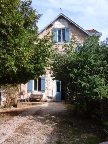 una casa de piedra con una puerta azul y árboles en La Maison Bleue, en Brantôme