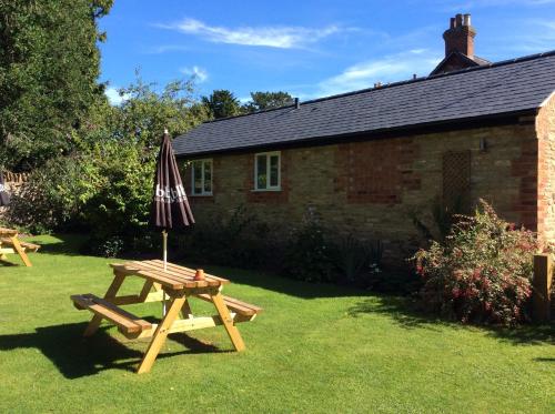 a picnic table with an umbrella in front of a house at Three-Cranes in Turvey