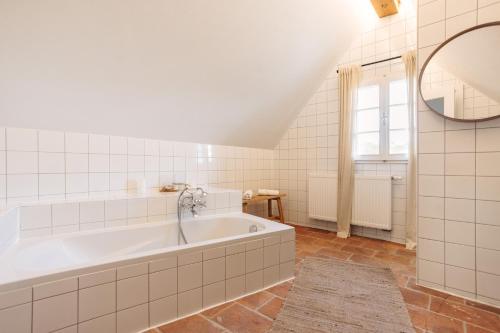 a white bathroom with a tub and a window at Das KRANACH 28 in Fötschach
