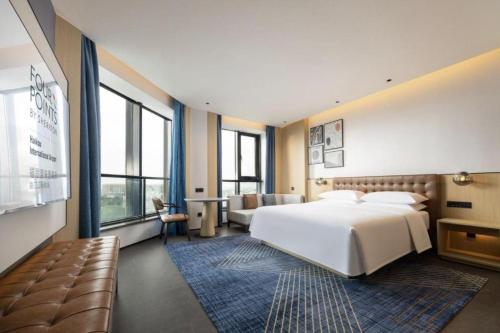 a bedroom with a large white bed and a couch at Four Points by Sheraton Haikou International Airport in Haikou