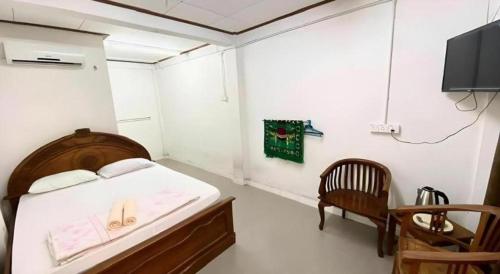 a bedroom with a bed and a chair and a tv at Nipah River view in Kampong Losong