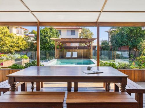 a patio with a table and benches and a swimming pool at Mariners Rest in Yamba
