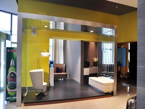 a room with a white chair and a yellow wall at Jinjiang Inn Luoyang Nanchang Road Wangfujing in Luoyang