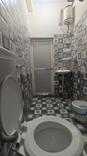 a bathroom with a toilet and a tiled floor at Hotel Priyanshi Palace in Ujjain