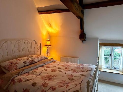 ein Schlafzimmer mit einem Bett mit geblümter Tagesdecke in der Unterkunft Charming Grade 2 Cottage w/ Garden in Warminster in Warminster