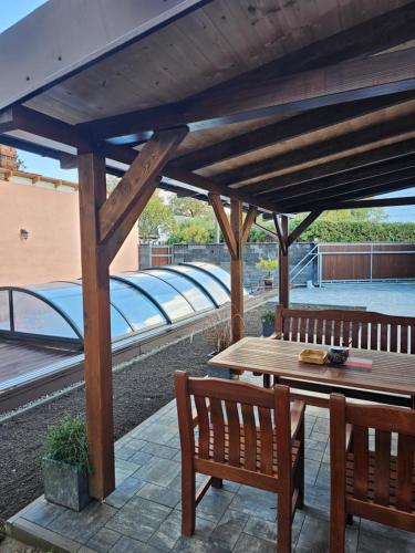 una pérgola de madera con una mesa de madera y dos bancos en Apartmán Fany III, en Zlaté Hory