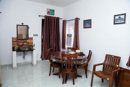 een eetkamer met een tafel en stoelen bij Cherry Blossom in Kotagiri